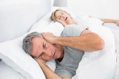 man unable to sleep due to his wife's snoring caused by sleep apnea