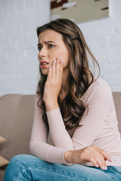 woman holding her tooth in pain